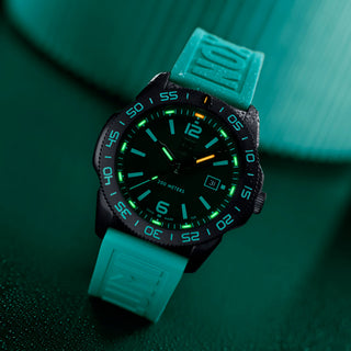 Teal wristwatch with a dark face on a green textured surface